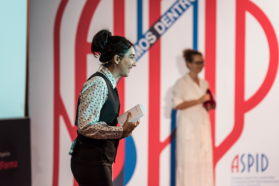 La presentadora en primer plano con la Presidenta Raquel Mizrahi de fondo